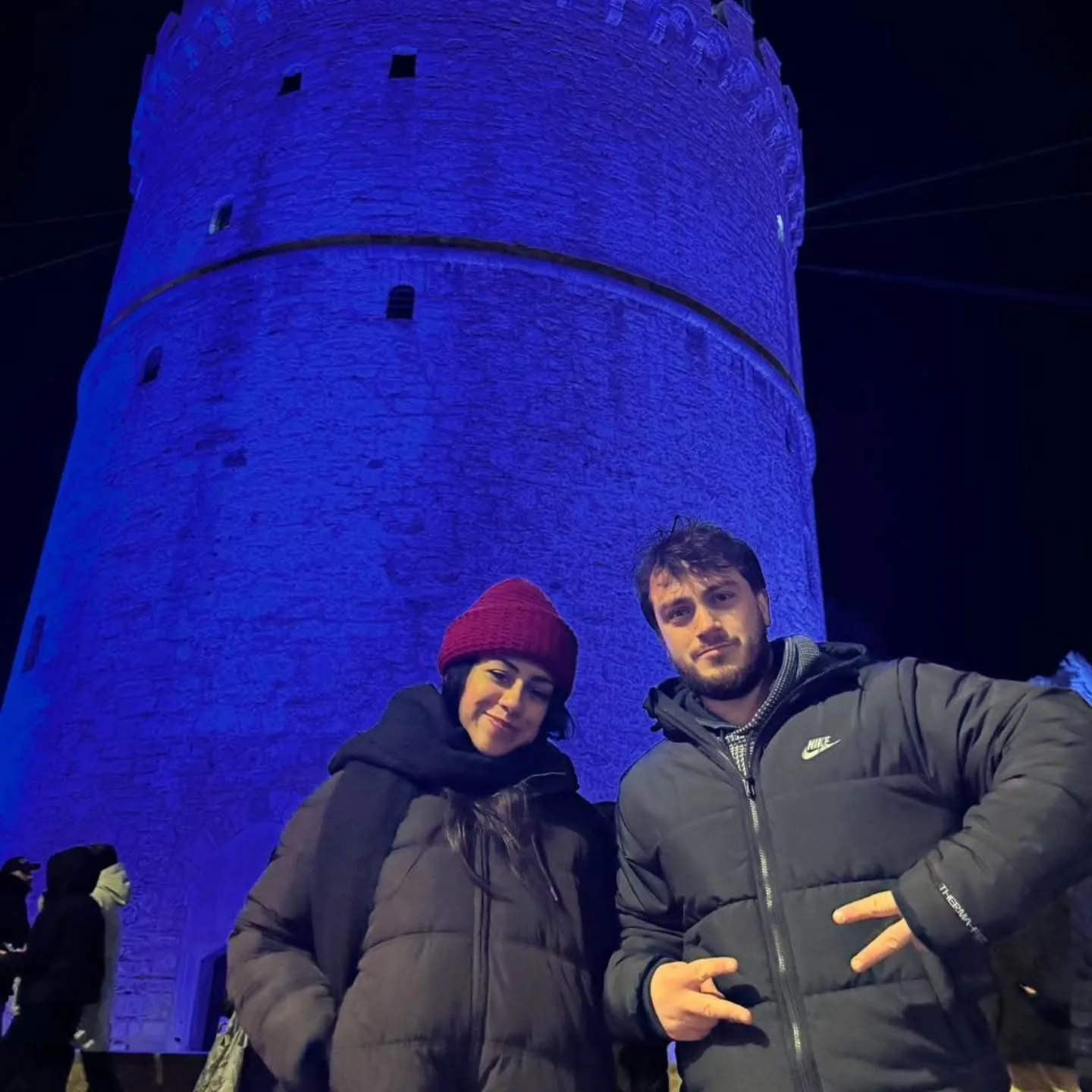 Cristal and me in front of a blue-lit stone tower at night